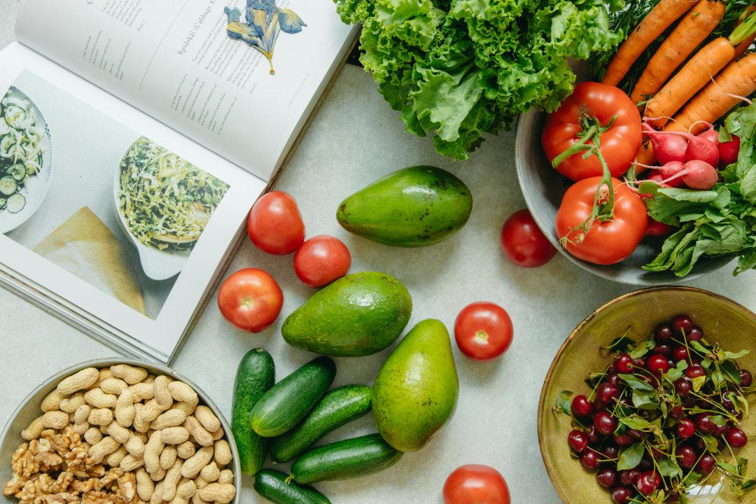 A colorful arrangement of fresh fruits, vegetables, nuts, and fish on a wooden table.