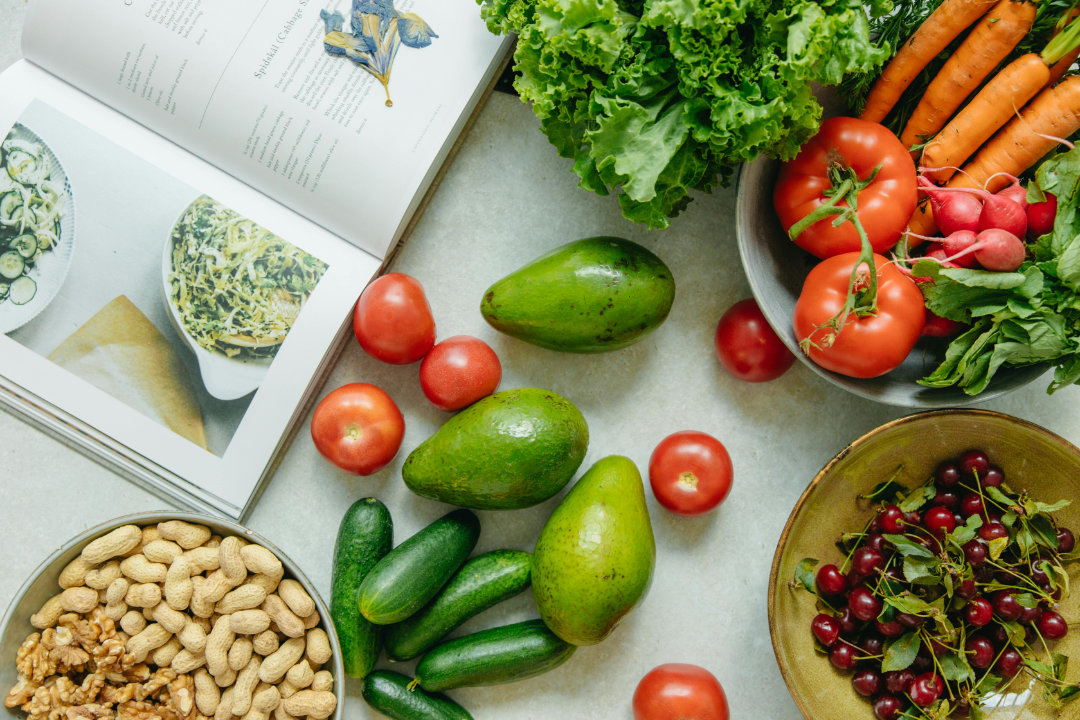 A colorful arrangement of fresh fruits, vegetables, nuts, and fish on a wooden table.